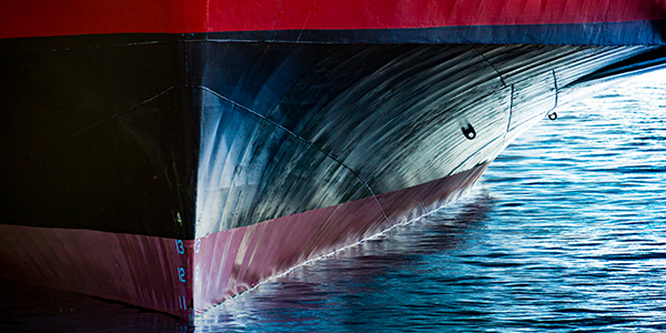 Bottom of red and black container ship touching water.