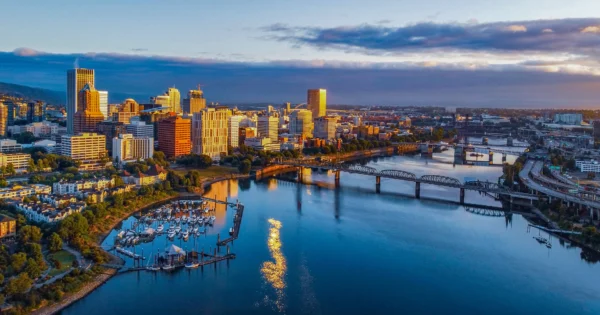 Aerial view of downtown Portland, Oregon at sunrise with high-rise buildings, Willamette River, bridges, and waterfront marina.