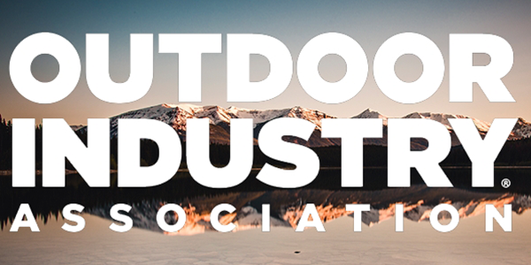 Logo of Outdoor Industry Association in bold white text over a scenic mountain landscape with snow-capped peaks and calm water reflection.