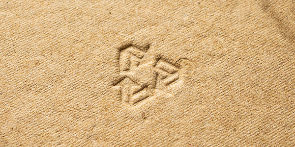 Primer plano del símbolo de reciclaje en relieve sobre papel kraft marrón, que representa materiales de envasado ecológicos y sostenibles.