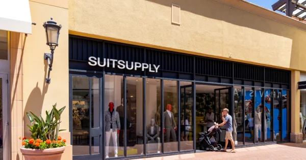Cảnh bên ngoài của một cửa hàng bán lẻ Suitsupply với cửa sổ kính trưng bày ma-nơ-canh mặc vest trang trọng và một biển hiệu lớn màu đen có chữ màu trắng.