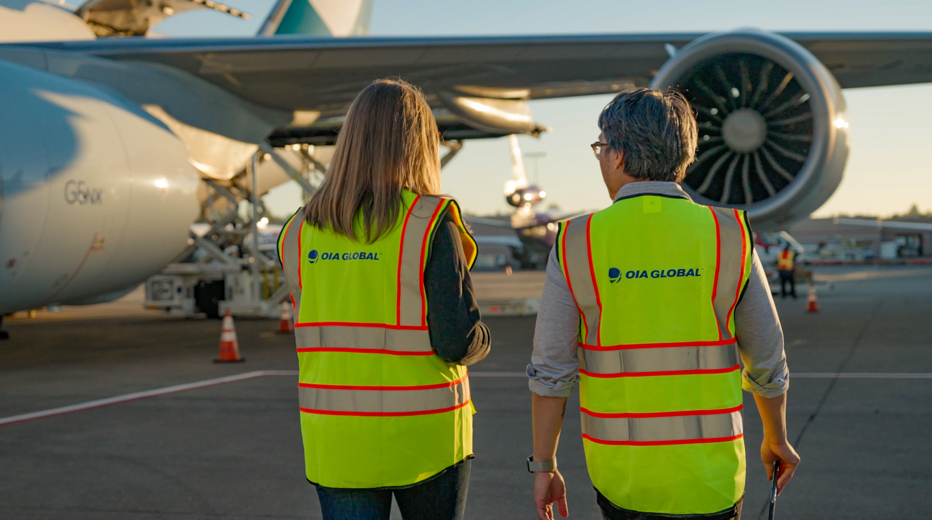 OIA Global thông điệp thương hiệu mới của, được thể hiện qua hai nhân viên vận hành vận tải hàng không.
