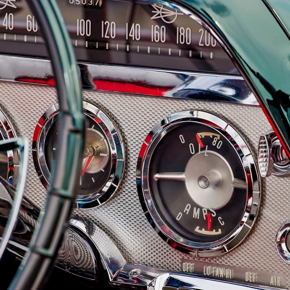 Close-up of vintage car dashboard with analog gauges, speedometer, and chrome detailing.