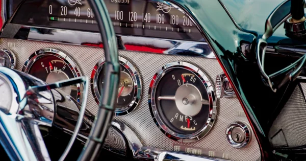 Close-up of vintage car dashboard with analog gauges, speedometer, and chrome detailing.