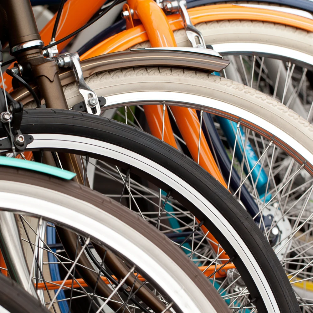 Close-up of stacked bicycles showing wheels, spokes, and colorful frames in retail or warehouse setting.