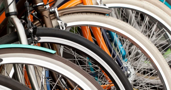 Close-up of stacked bicycles showing wheels, spokes, and colorful frames in retail or warehouse setting.