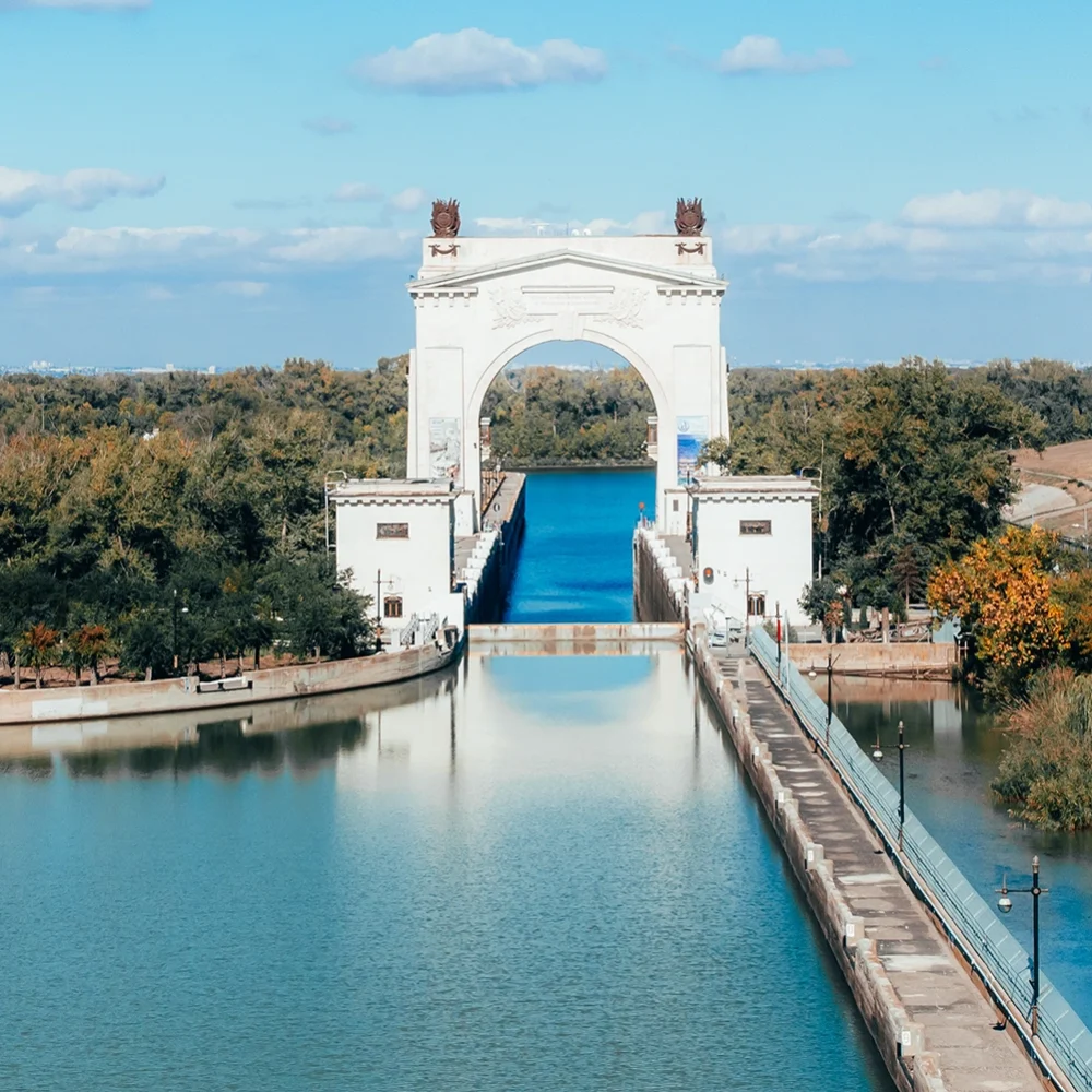 Large canal lock with white arch structure and waterway surrounded by trees, part of the Volga-Don Canal in Russia.