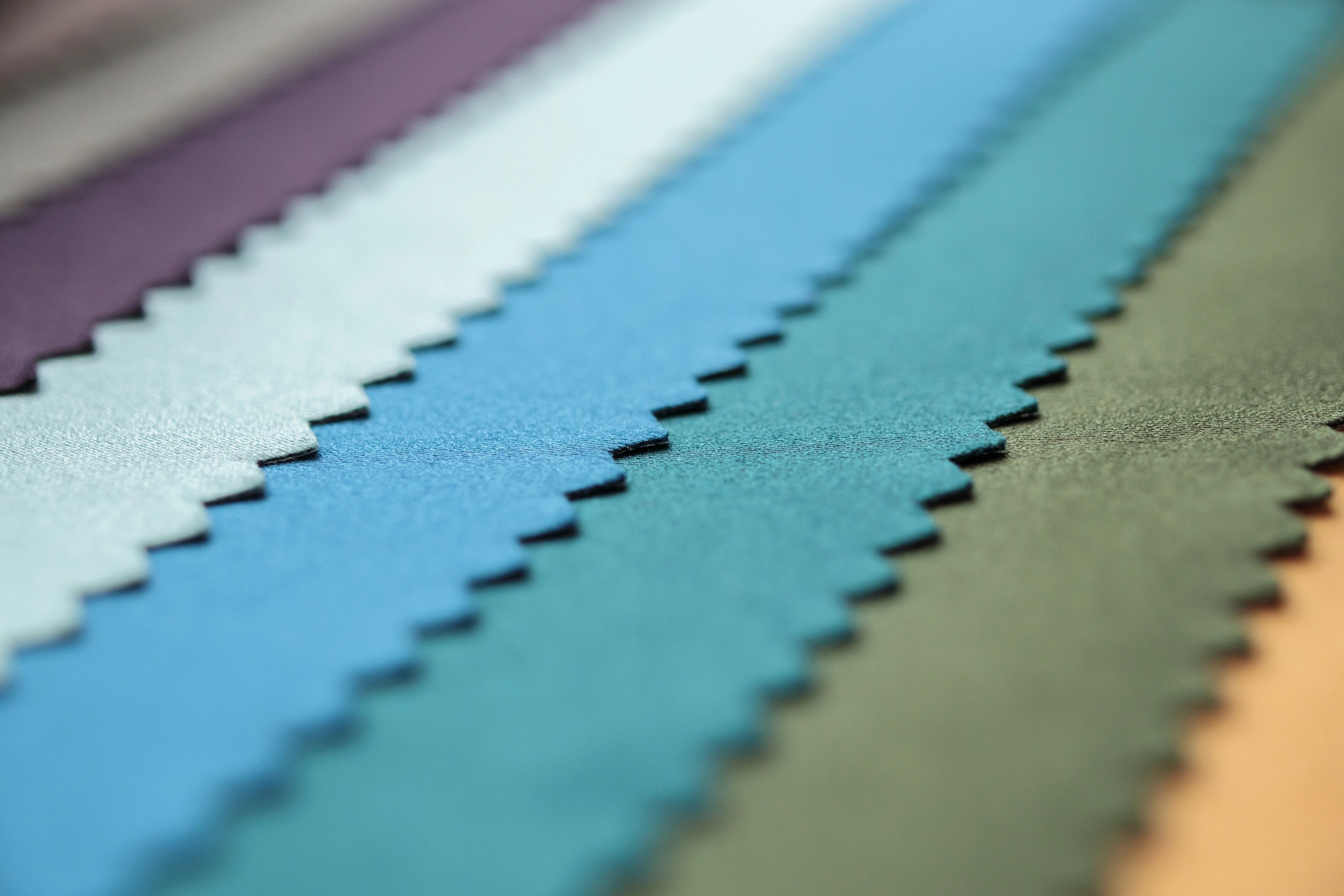 Close-up of colorful textile fabric swatches arranged in layers, showing different material textures and finishes.