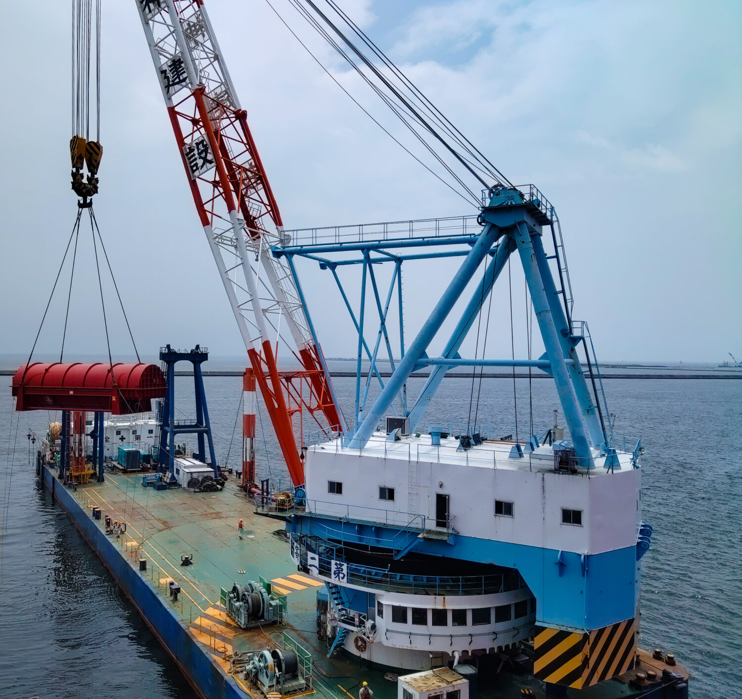 OIA completed a massive cost-saving breakbulk solution from Japan to Europe. This picture shows the gas turbine rotor in its enclosure as a floating crane lifts it for its journey to the Netherlands.