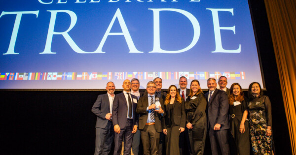 Group of professionals on stage receiving an award at Celebrate Trade event with large screen backdrop.