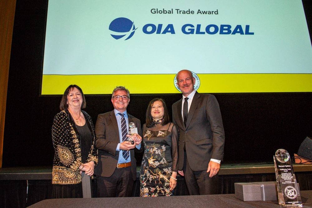 Representatives receiving a Global Trade Award for OIA Global on stage with branded backdrop.
