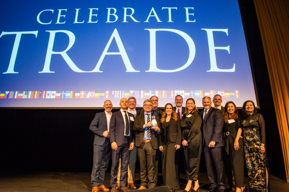 Group of professionals on stage receiving an award at Celebrate Trade event with large screen backdrop.