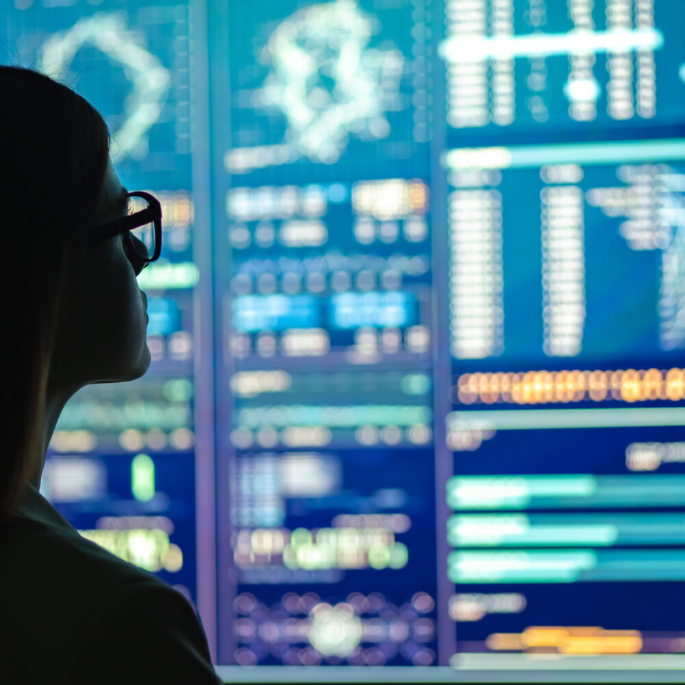 Businesswoman starting at dashboard screen of analytics, representing global logistics partner concept.