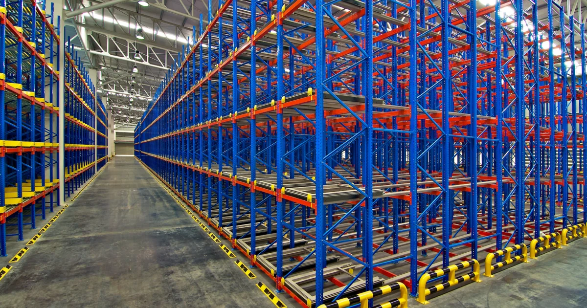 Empty warehouse with multi-level pallet racking system in blue and orange, designed for high-density storage and logistics operations.