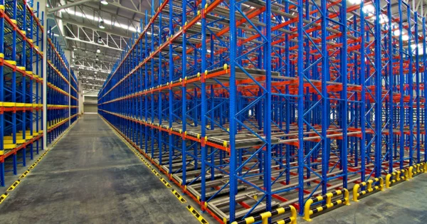 Empty warehouse with multi-level pallet racking system in blue and orange, designed for high-density storage and logistics operations.