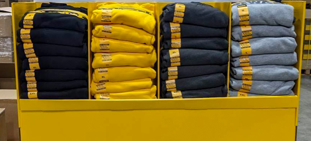 Display de ponto de venda com roupas pretas e amarelas dentro de uma loja.