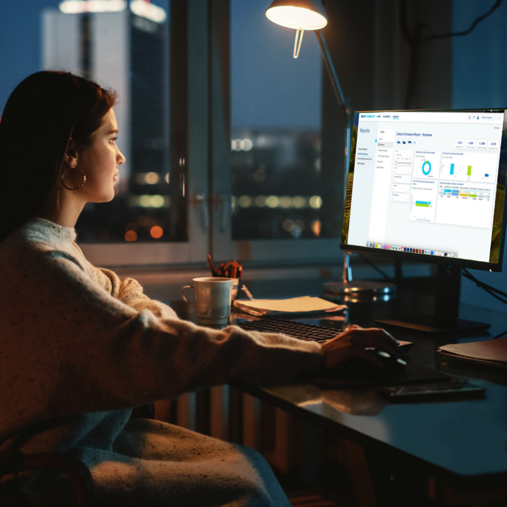 Woman sitting at desktop monitor reviewing OIA Connect reporting functionality.