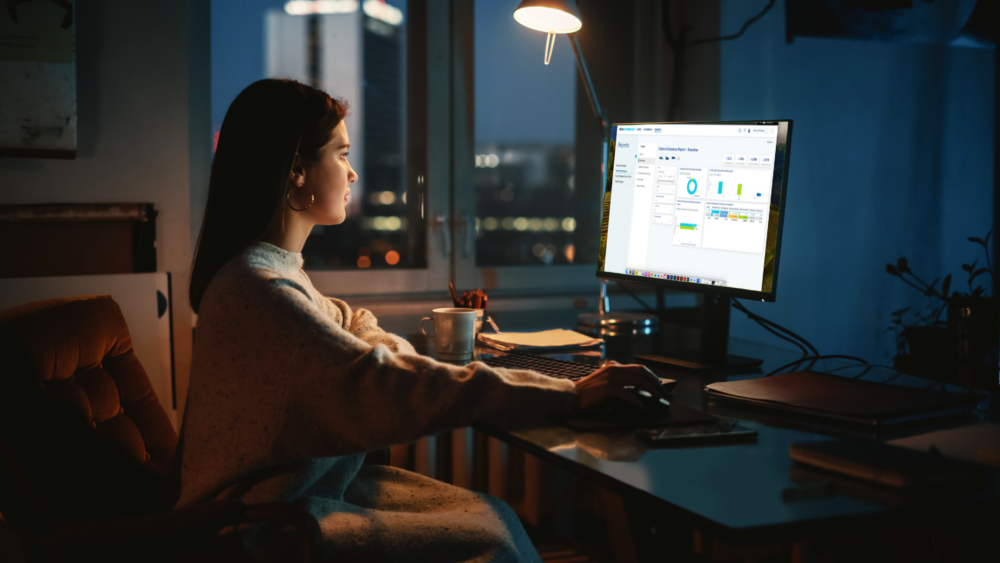 Woman sitting at desktop monitor reviewing OIA Connect reporting functionality.