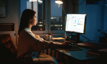 Woman sitting at desktop monitor reviewing OIA Connect reporting functionality.