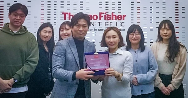 Team members holding Thermo Fisher Scientific award for best service provider at office location in Korea.