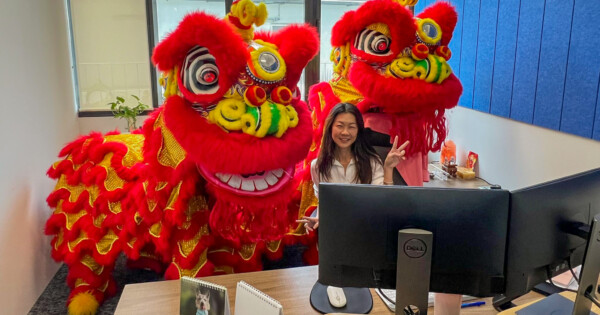 Traditional Chinese lion dance costumes inside an office with employee at desk, celebrating a cultural event.