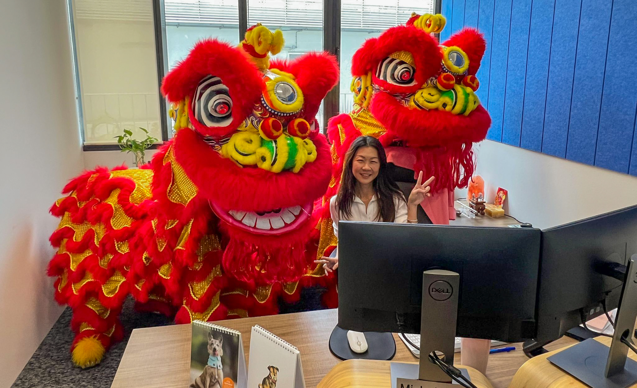 Woman at desk in OIA Singapore Tai Seng Exchange surrounded by two large, artistic dragon costumes.