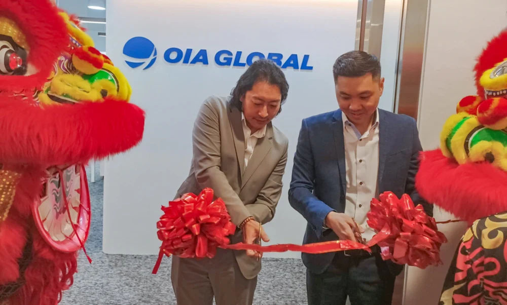 Ribbon cutting ceremony with executives and lion dance performers at OIA Global office opening.