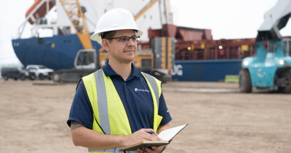 OIA Global careers concept showing oia employee in hard hat and blue branded polo shirt with bright visibility work vest.