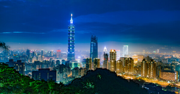 Taipei city skyline at night with illuminated Taipei 101 skyscraper and surrounding buildings.