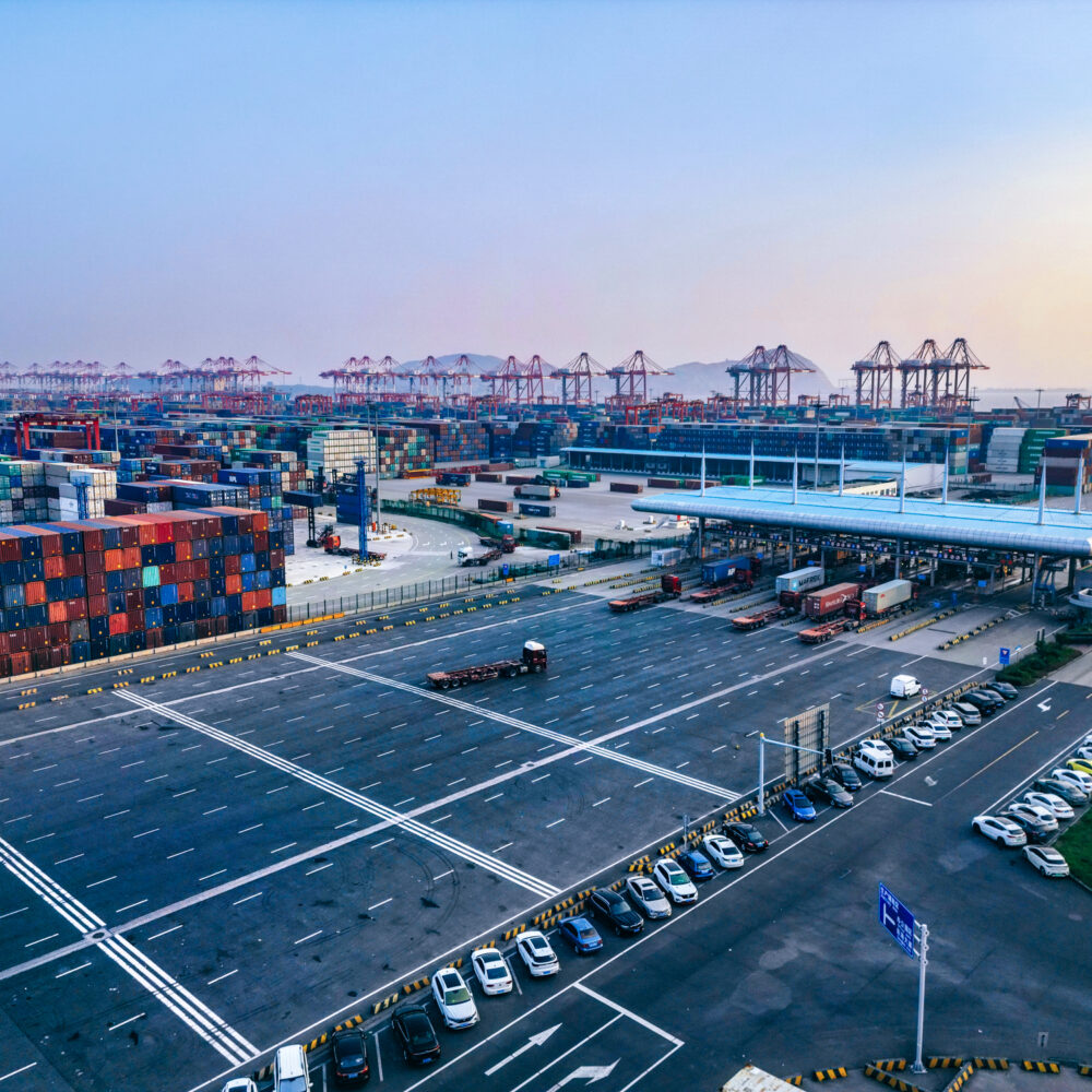 Foreign trade zone facility with bonded warehouse and port containers in background.