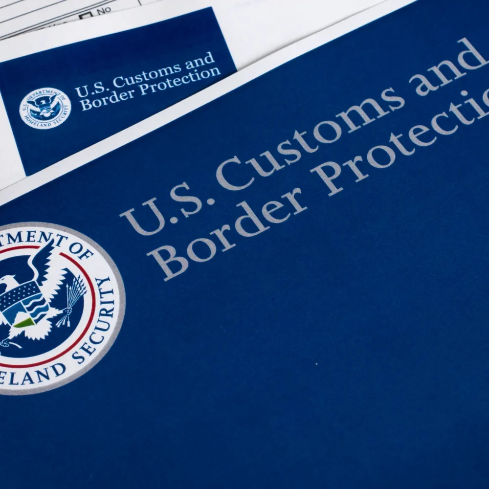 Close-up of U.S. Customs and Border Protection documents and Department of Homeland Security emblem on a blue folder with official paperwork.