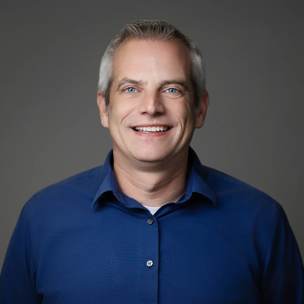 Professional portrait of OIA Global leadership team member wearing a blue collared shirt