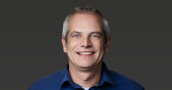Professional portrait of OIA Global leadership team member wearing a blue collared shirt