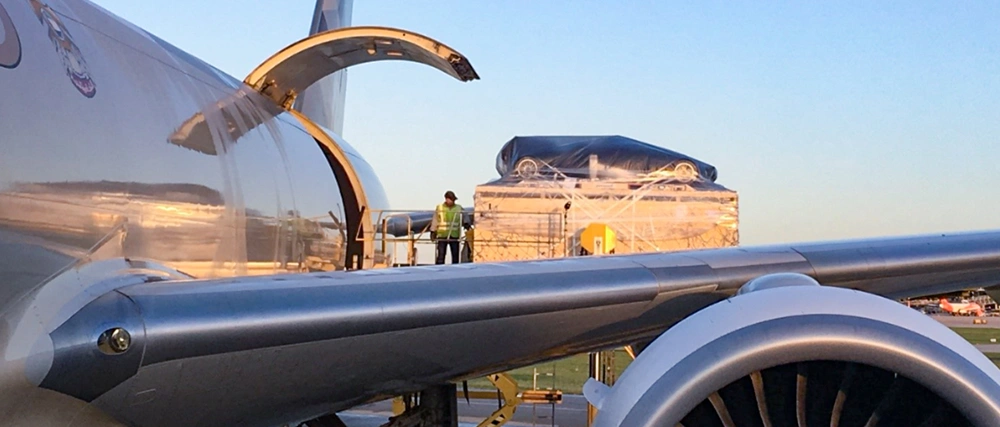 Cargo being loaded onto an aircraft with ground crew and large palletized shipment on airport tarmac.